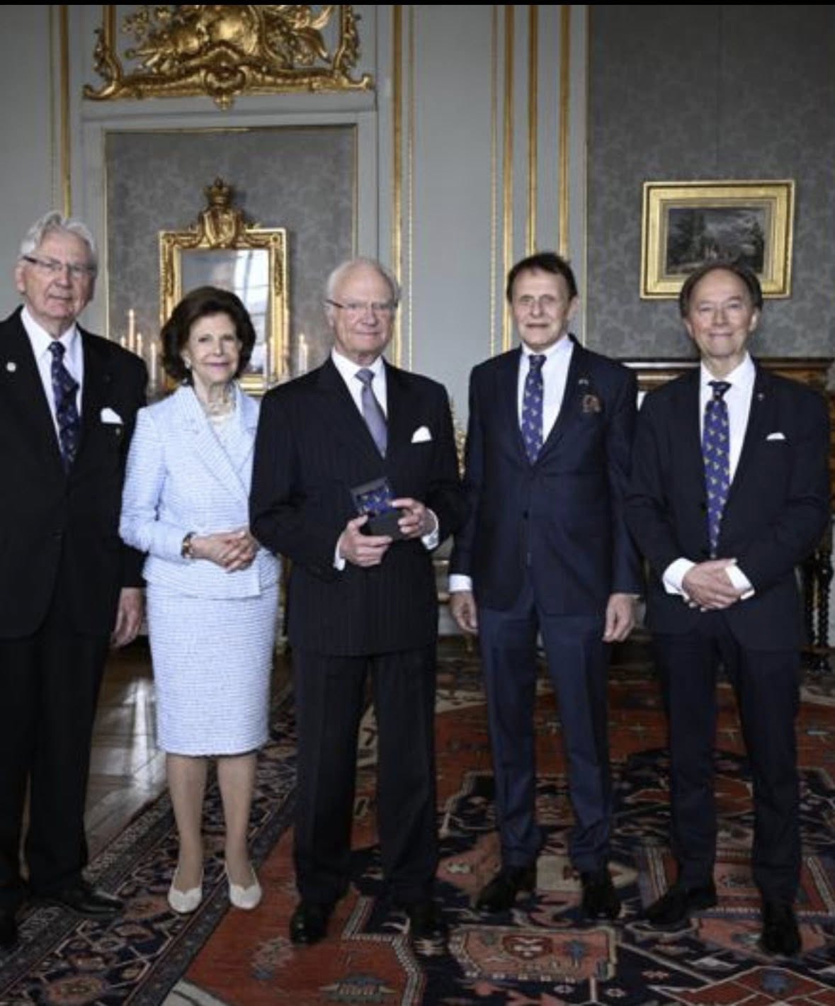Kung Carl XVI Gustaf med Drottning Silvia tar emot en specialdesignad slips från Svenska Slipsakademien på Stockholms slott